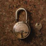 A close-up view of a vintage padlock with its key on a stone surface.