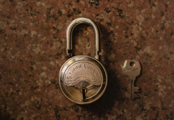 A close-up view of a vintage padlock with its key on a stone surface.