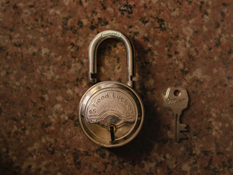 A close-up view of a vintage padlock with its key on a stone surface.